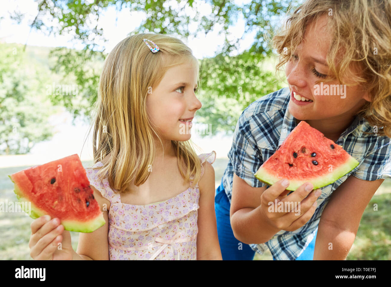 Children hold fresh melon pieces as a healthy diet at the camera Stock Photo