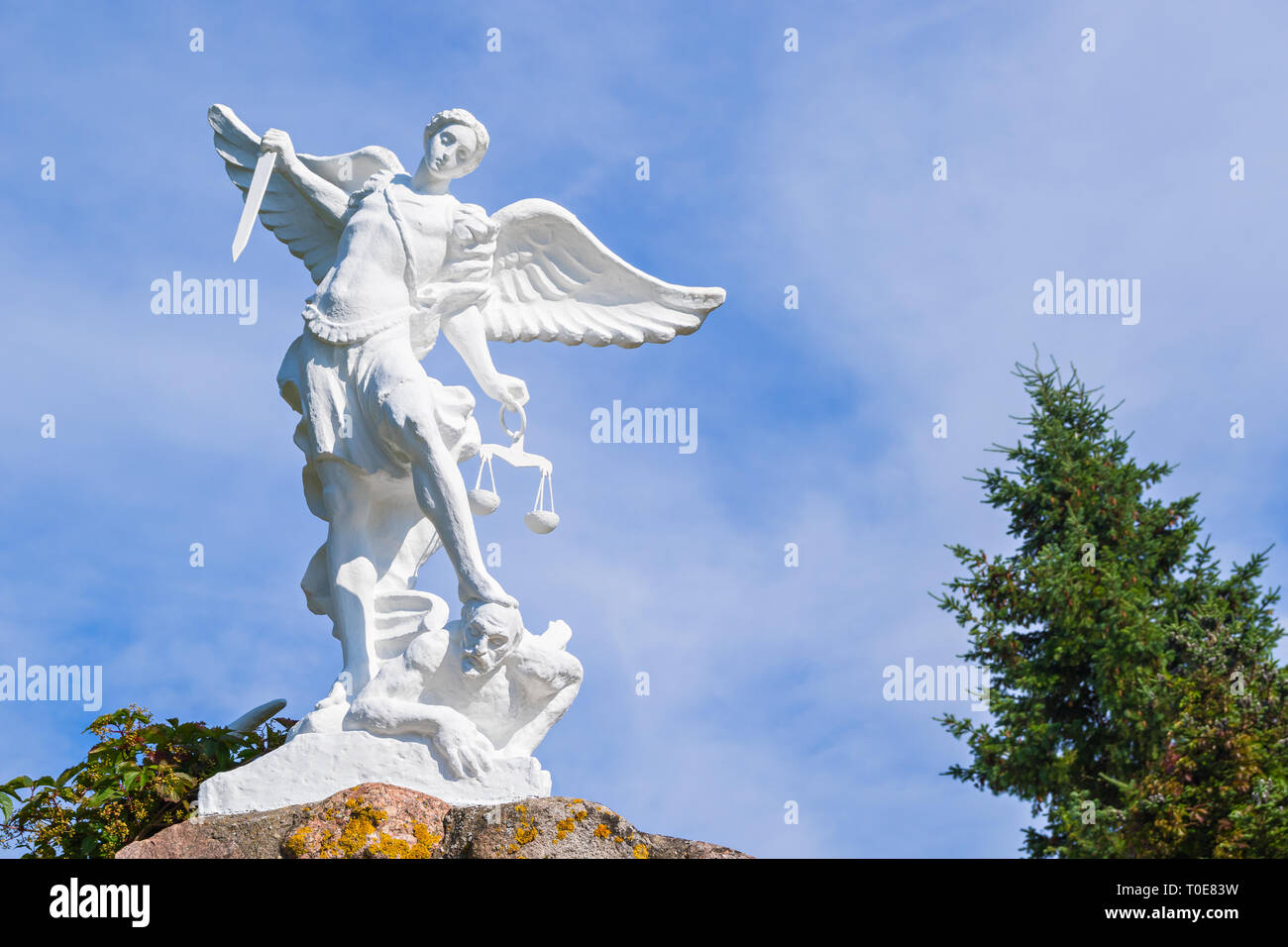 Sculpture of St. Michael the Archangel with a sword and libra striking devil Stock Photo