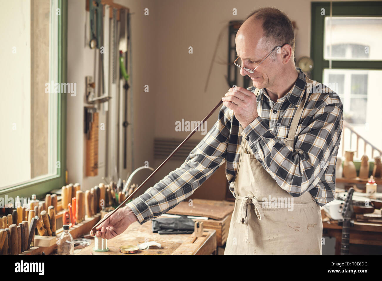 Violin maker inside the is checking a bow with his eyes Stock
