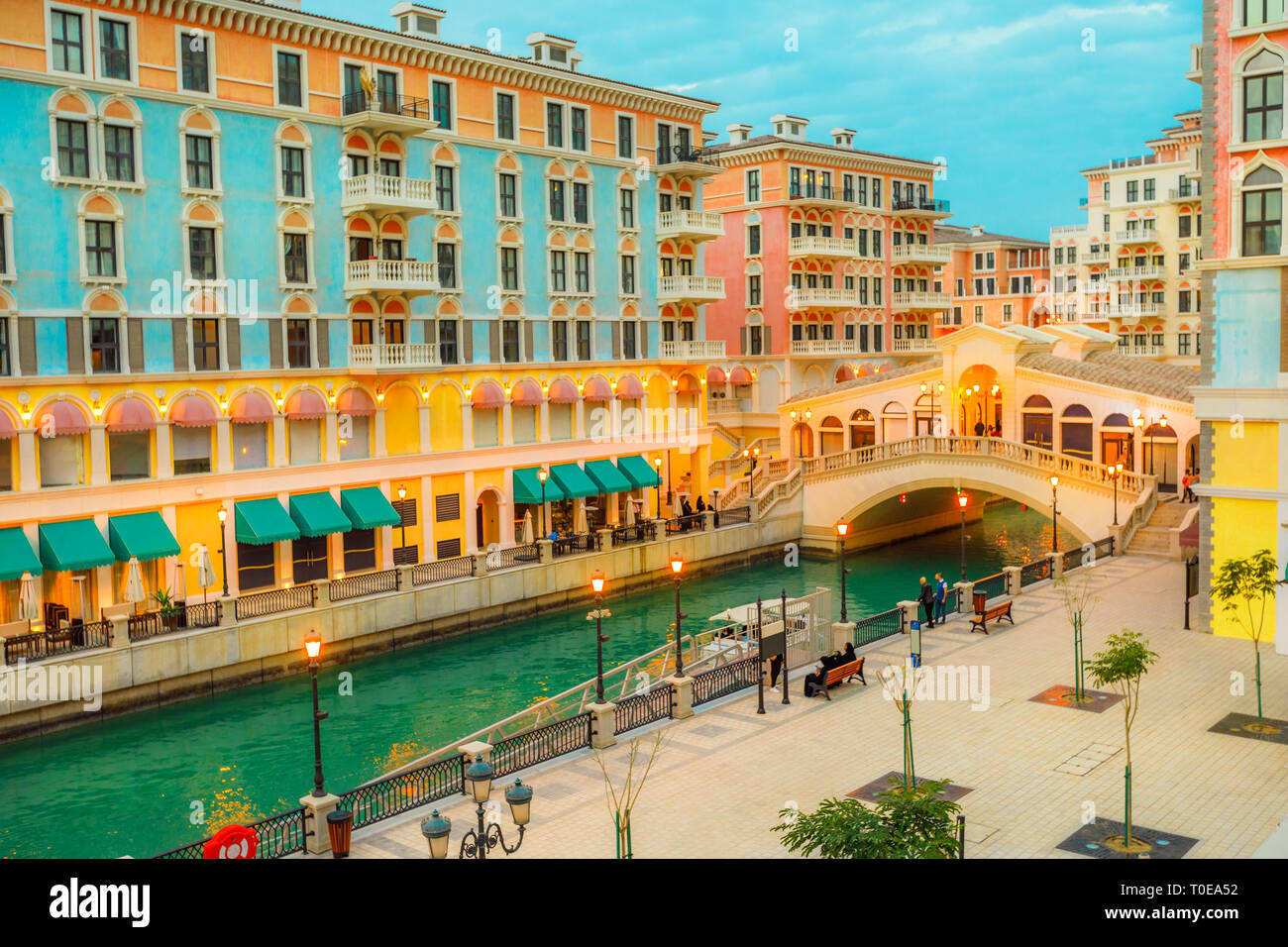 Aerial view of Venetian bridge and canals of picturesque and luxurious district of Doha illuminated at twilight. Scenary of Venice at Qanat Quartier Stock Photo
