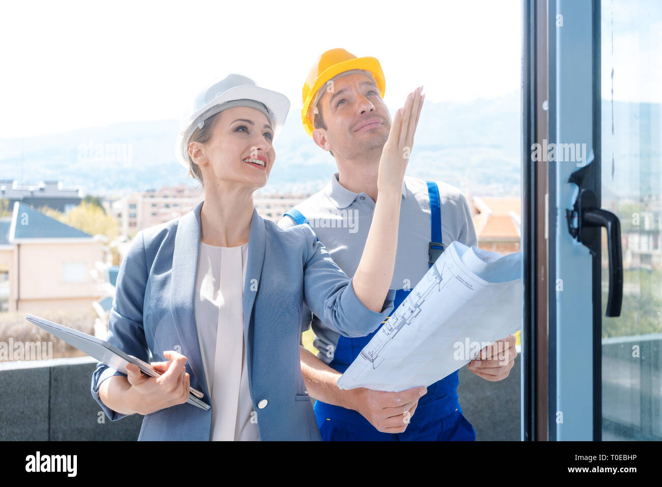 Architect and construction worker checking windows on site Stock Photo