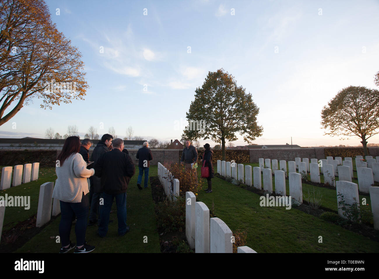 A tour guide shows tourists the graves of fallen soldiers of the first world war as they walk amidst headstones in a graveyard in France. Stock Photo