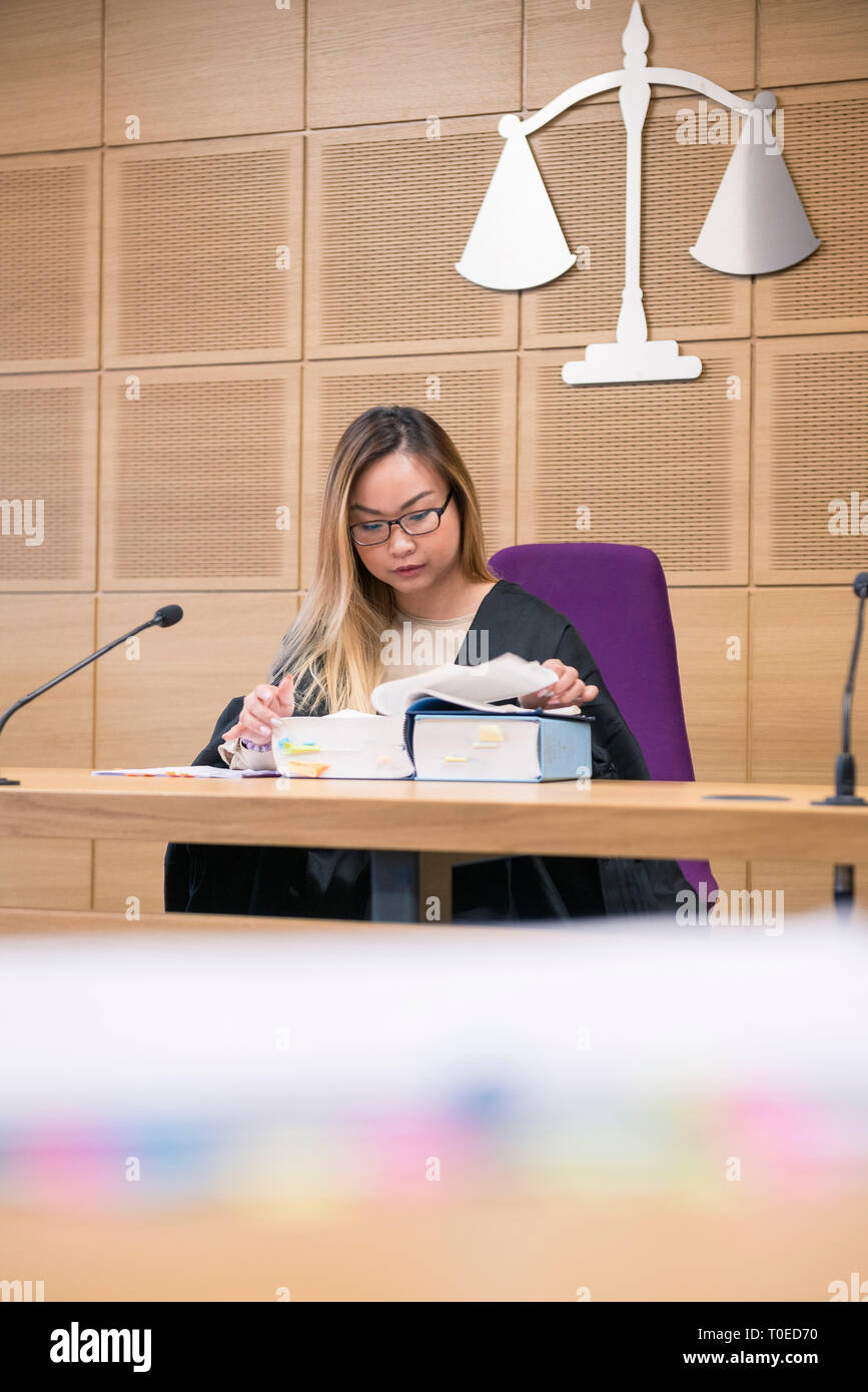 A young asian woman in a mock practice court of law at the University of Sussex practices her legal training while wearing robes Stock Photo