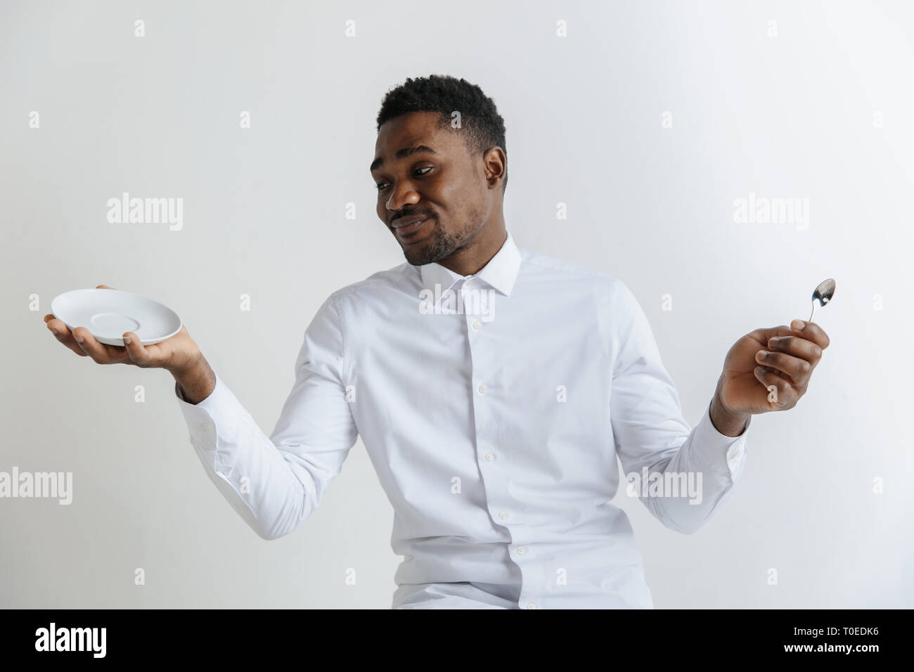 Young doubting attractive african american guy holding empty dish and ...
