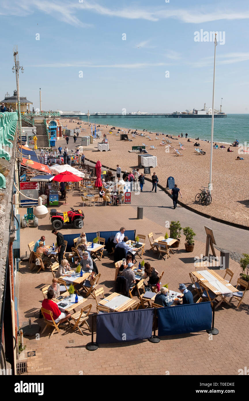 People sitting outside cafes on the promenade on the seafront in Brighton, Sussex, England. Stock Photo