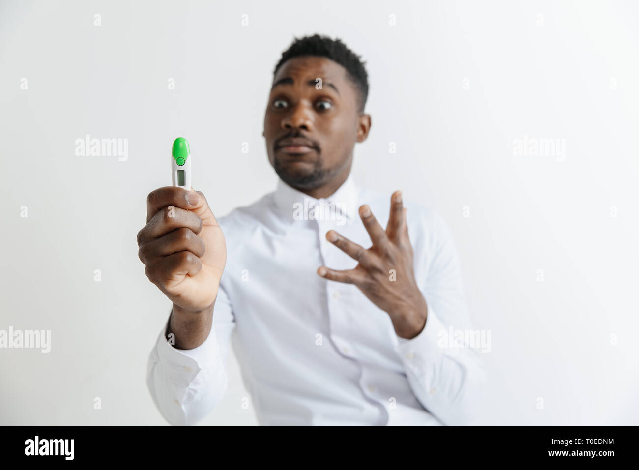 Young unhappy african american man looking at pregnancy test. Handsome sad man frustrated and having problems. Guy depressed because of result of pregnancy test Stock Photo