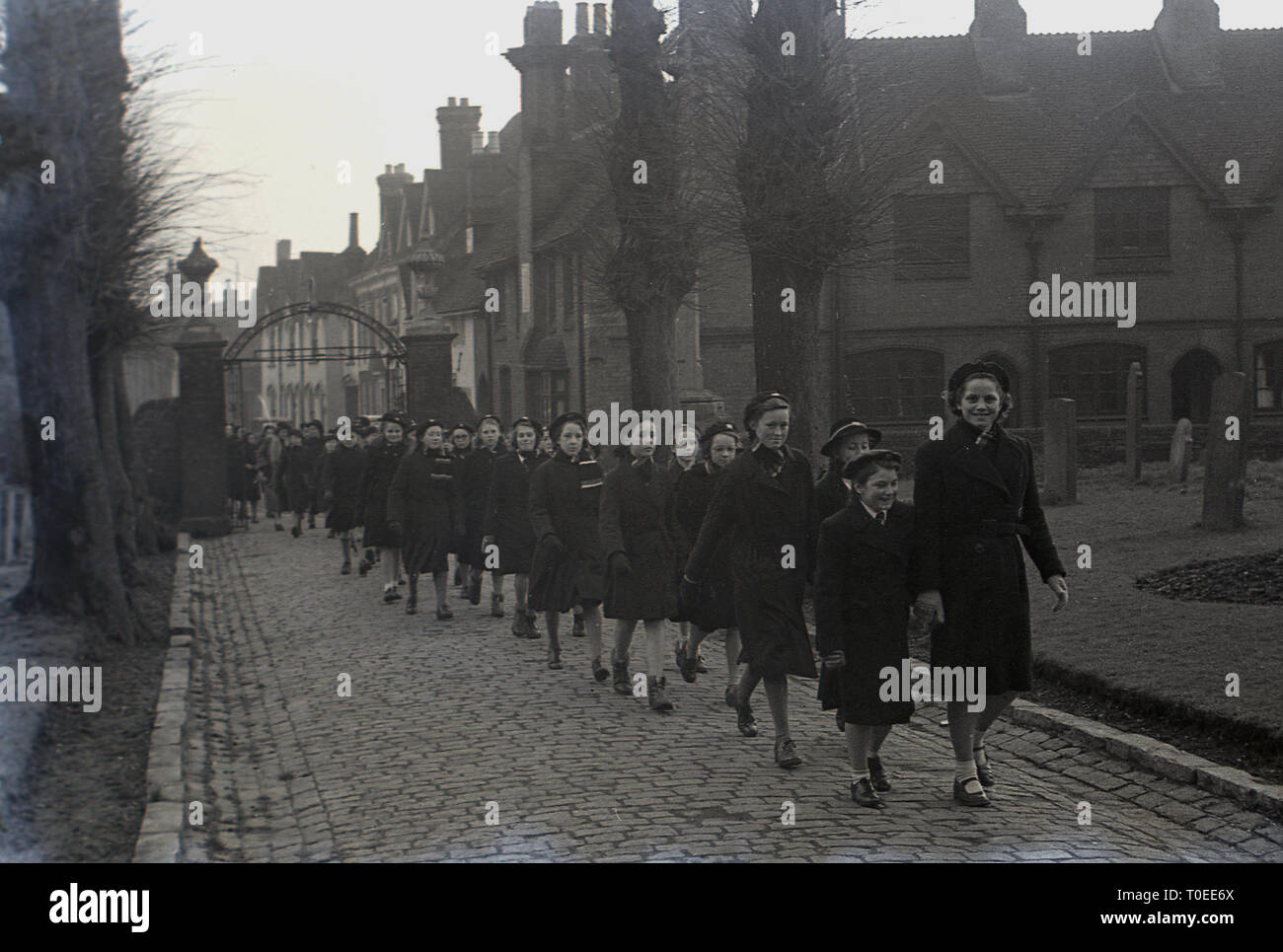 1948, a group of boarding school children walking on a cobbled path inside church grounds on the way to a Sunday service, England, UK. Stock Photo