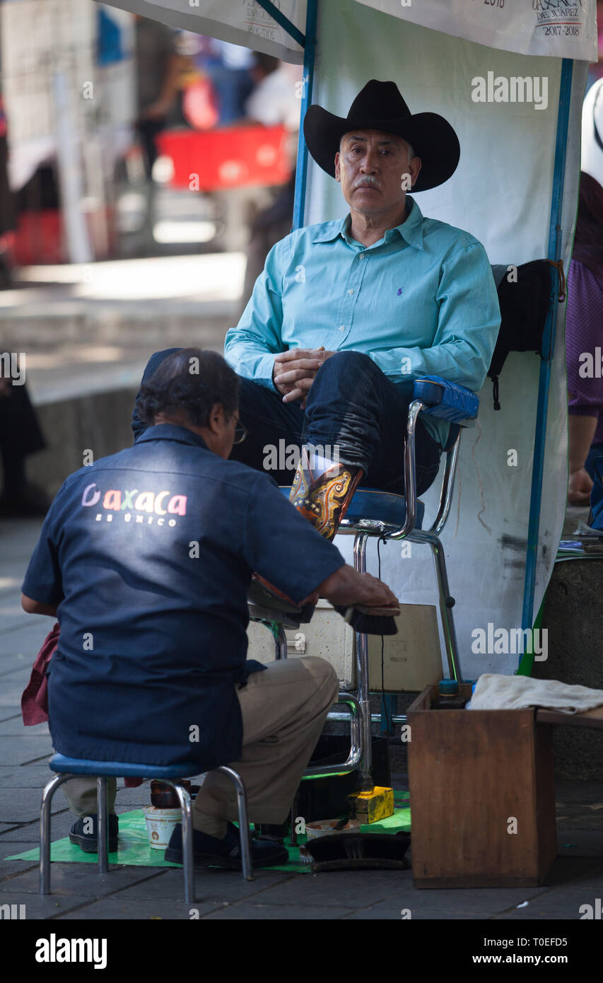 A man has his boots cleaned and polished at a shoe shine stand in the Zócalo in Oaxaca, Mexico, March 8, 2019. Stock Photo