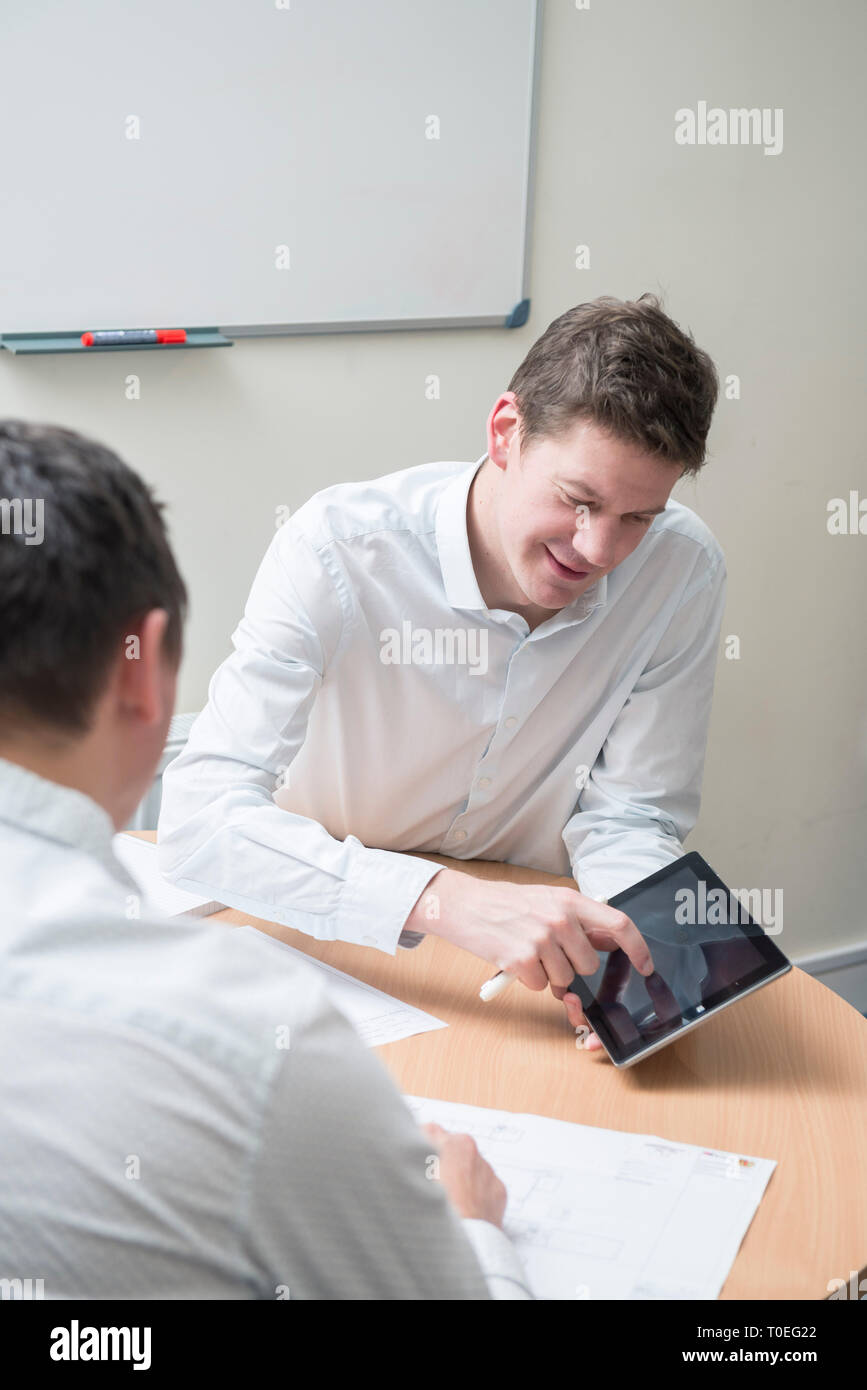 Men Roud Table Talk Two men sit round a table in a small office meeting room to review ...