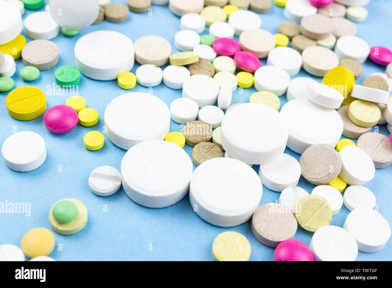 Assorted pharmaceutical medicine pills, tablets and capsules over blue background Stock Photo