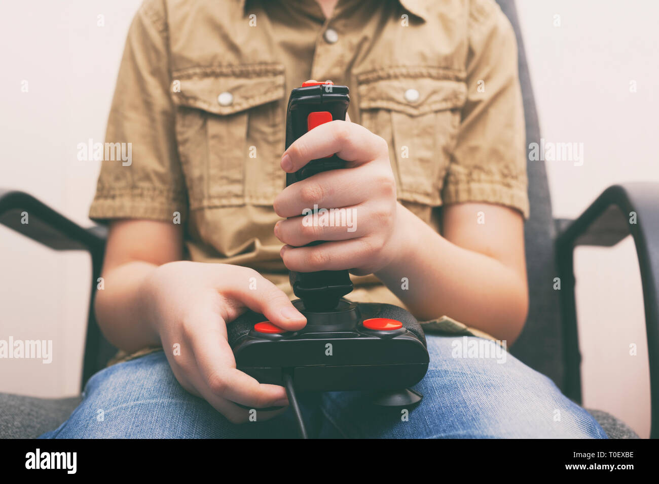 Young boy playing video game with a retro joystick. Gaming joystick from the mid-1980s. Close up. Stock Photo
