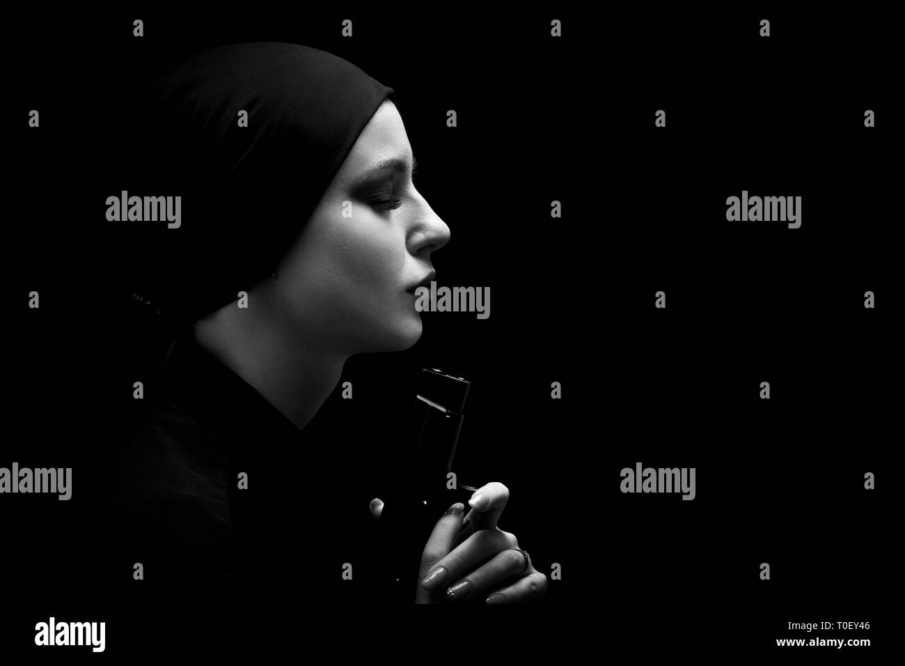 serious girl with gun profile on black background, side view