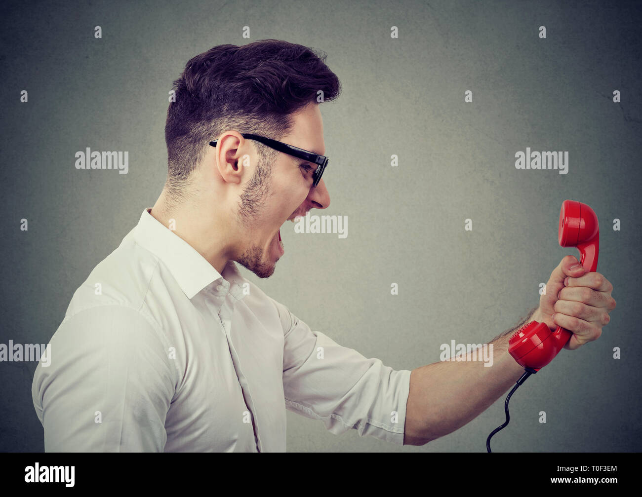 Angry business man yelling on a red telephone Stock Photo
