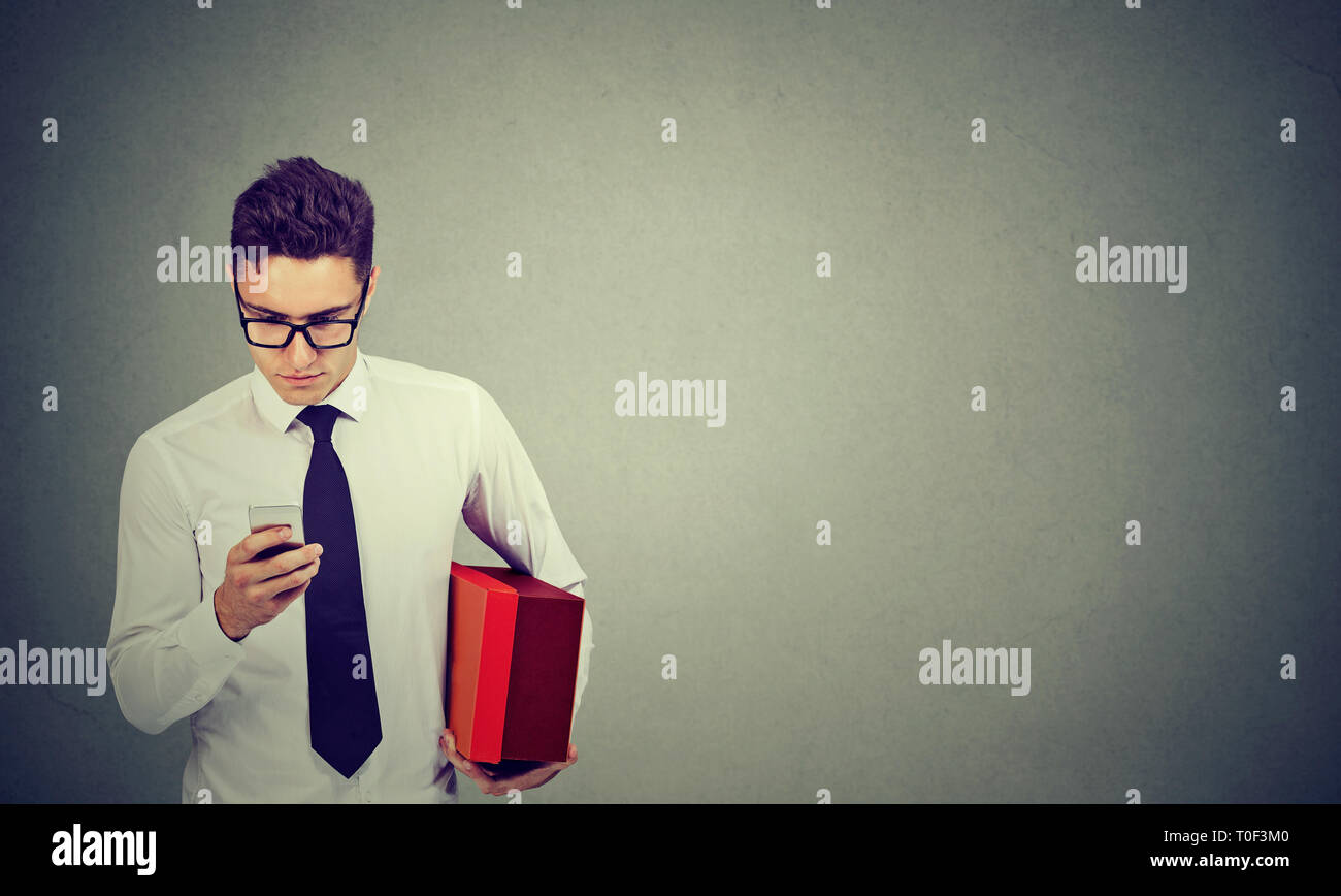 Businessman using cellphone holding a delivery box Stock Photo