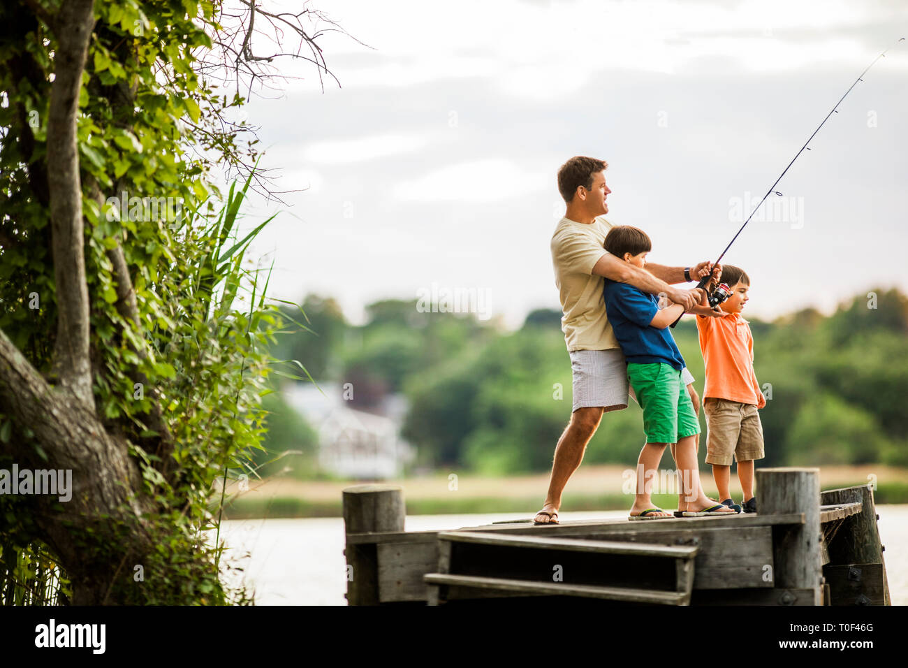 Father and sons fishing from a pier Stock Photo - Alamy