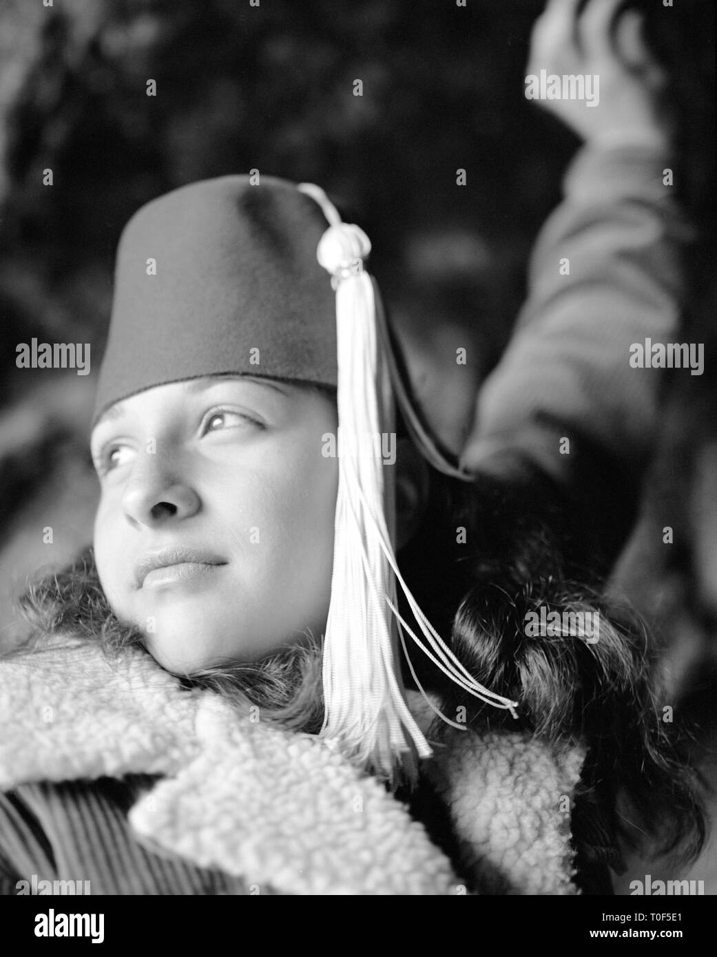 Teenage girl wearing a fez hat, looking away. Stock Photo