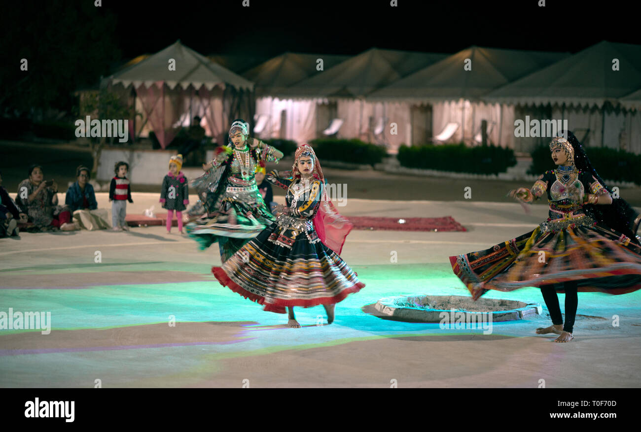 Three women in colourful dress perform a traditional folk dance in the Thar Desert, Rajasthan, India. Stock Photo