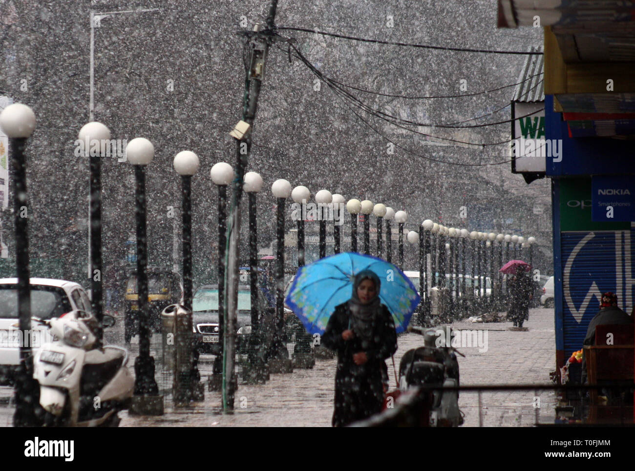 Srinagar, Kashmir. 20th March, 2019. A Kashmiri Girl holds umbrella as its fresh snow fall .Life in valley was affected on Wednesday due to a strike called by separatists to protest against the custodial death of a youth.©Sofi Suhail/Alamy Live News Stock Photo