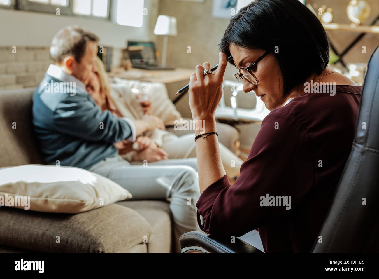 Thoughtful dark-haired woman leaning on her hand while analyzing the situation Stock Photo