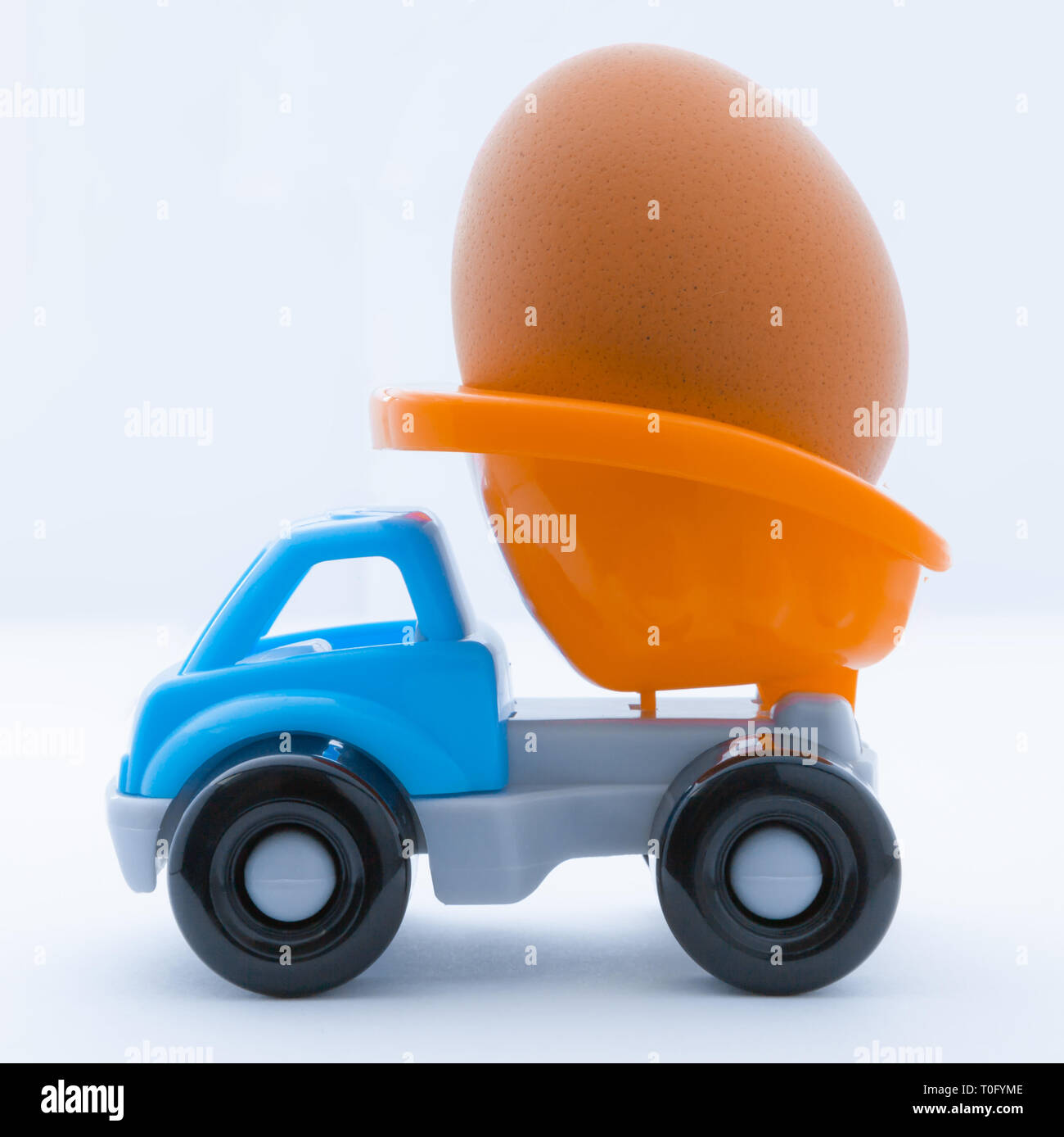 Colorful toy truck with a chicken egg in the back on a white background Stock Photo
