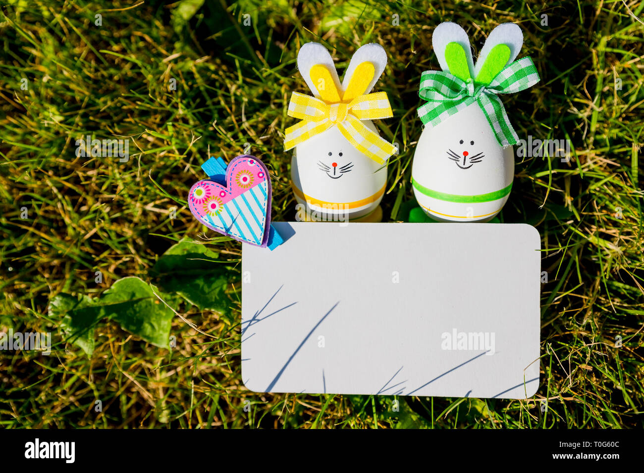 Blank greeting card with small easter eggs in the grass.Easter eggs on meadow. Spring holidays concept .Easter composition with easter eggs .Mockup Stock Photo