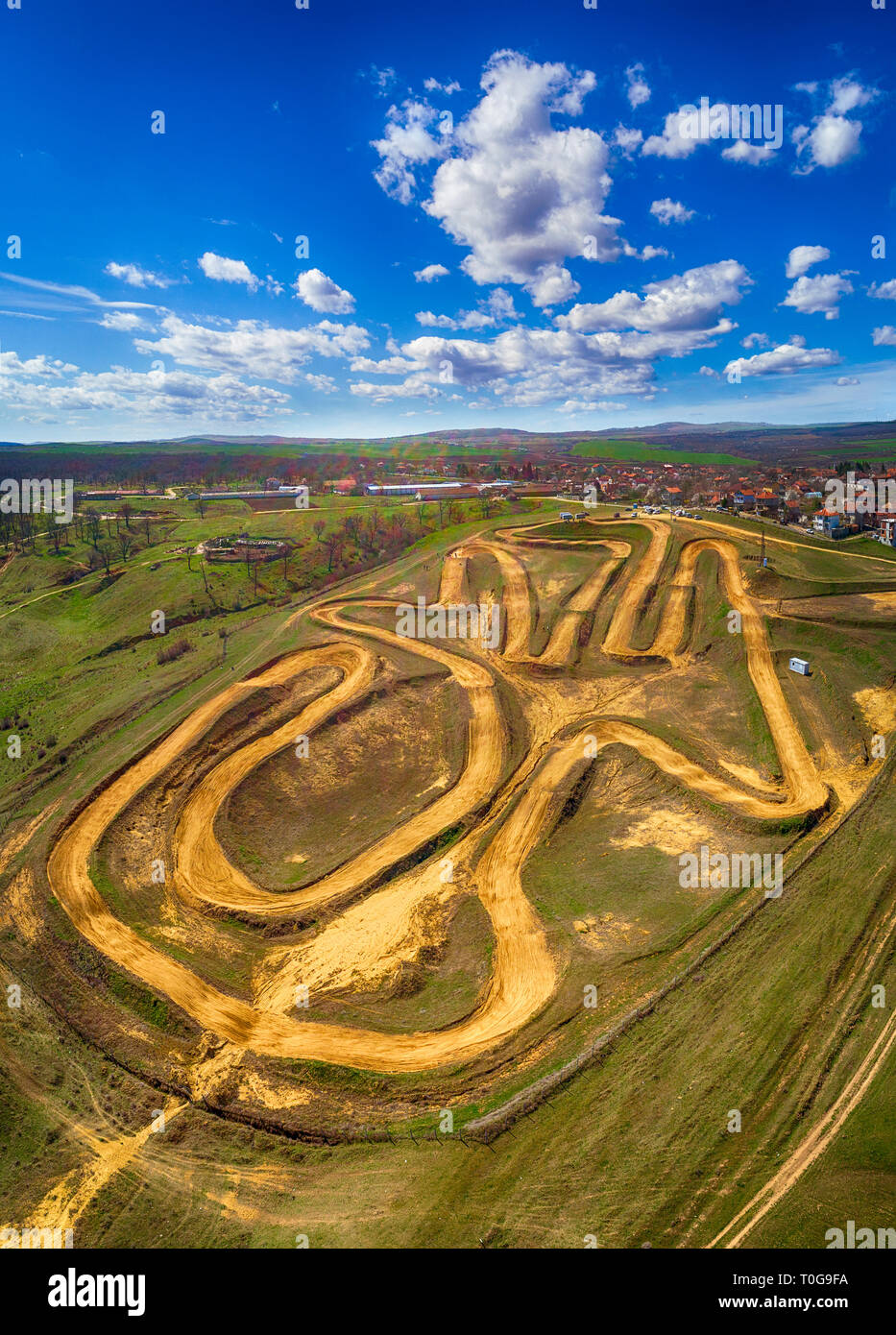 Aerial top down photo of motocross track showing the high-performance off-road motorcycles racing on the enclosed manmade dirt circuit with steep jump Stock Photo