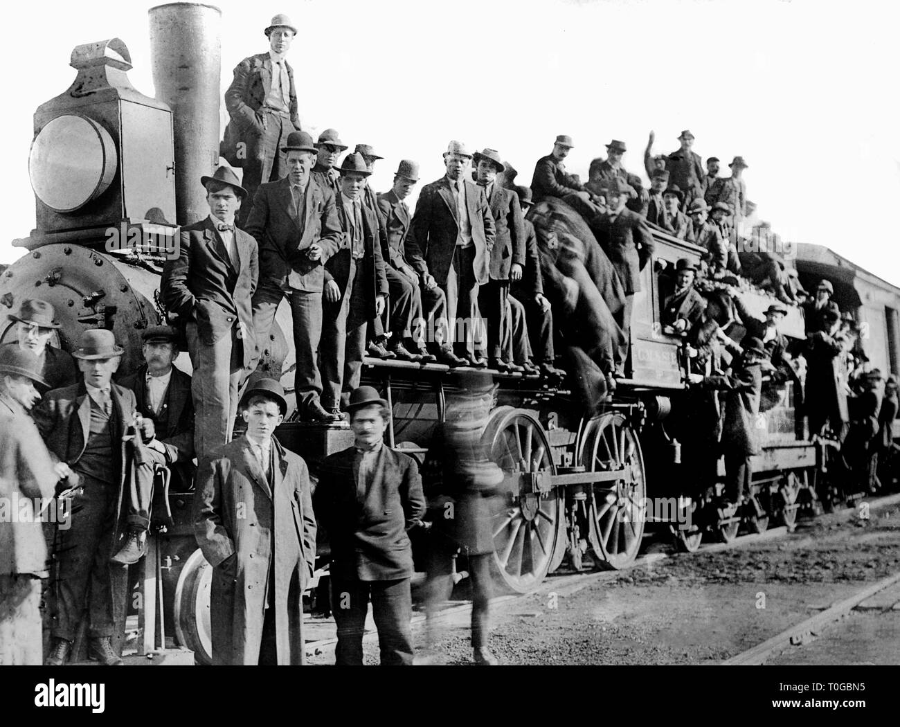 A crowd of men gathers on and around a Chicago, Milwaukee,  & St. Paul locomotive in Ladd, Illinois in 1909. Stock Photo