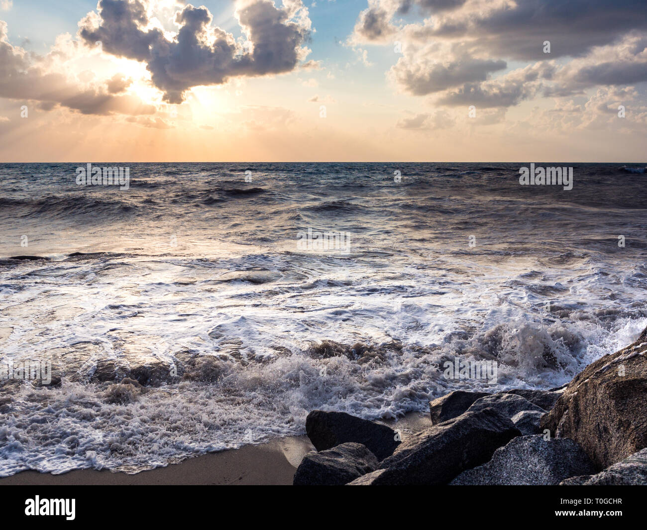 Sunset beach with rough seas and crashing waves. Stock Photo