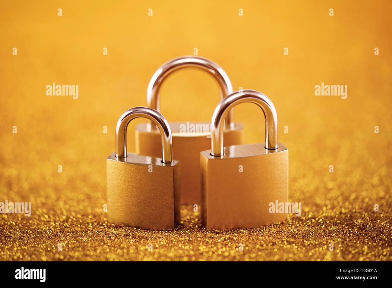 Security concept with three metal padlocks over golden background Stock Photo