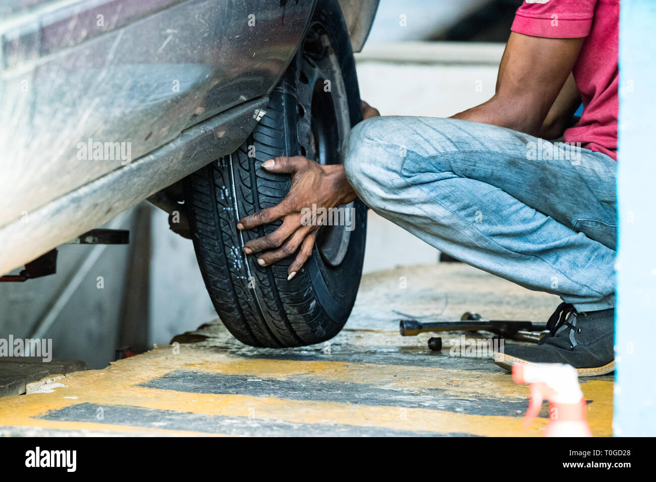 Tyre repairman changing a wheel on a car in Galle, Sri Lanka. Stock Photo