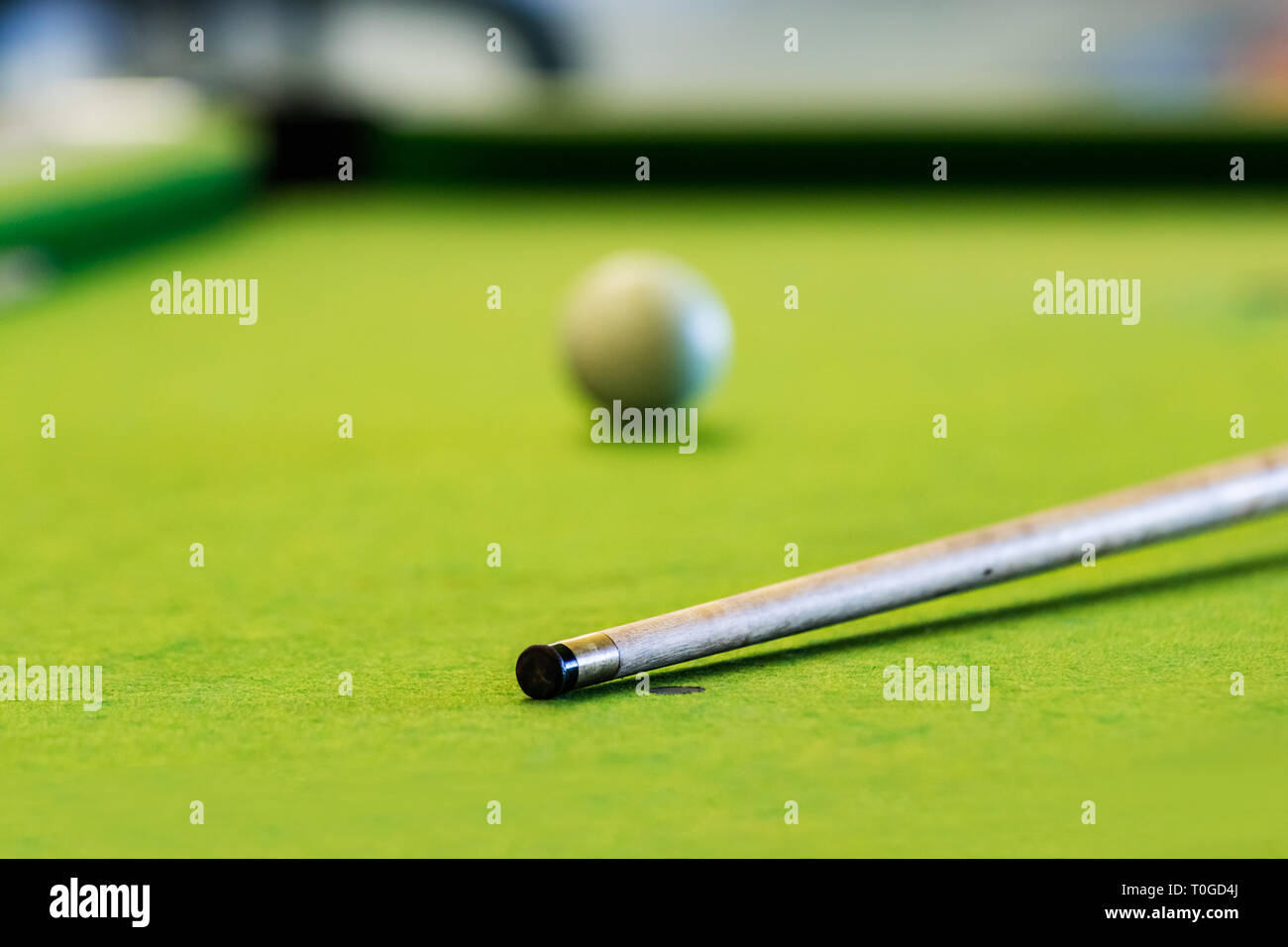 Closeup of a pool cue stick over a blurred white ball background. Stock Photo