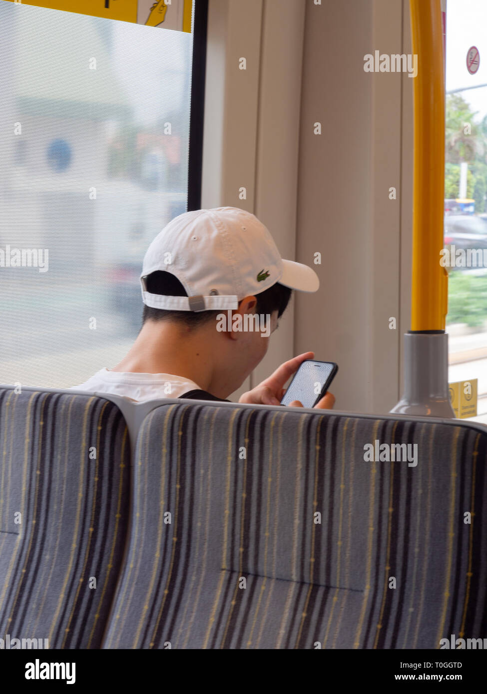 Passenger Looking At Their Phone While Riding A Tram Stock Photo