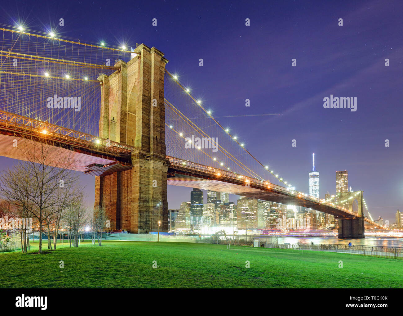 Brooklyn Bridge over East River at night in New York City Manhattan with green park Stock Photo