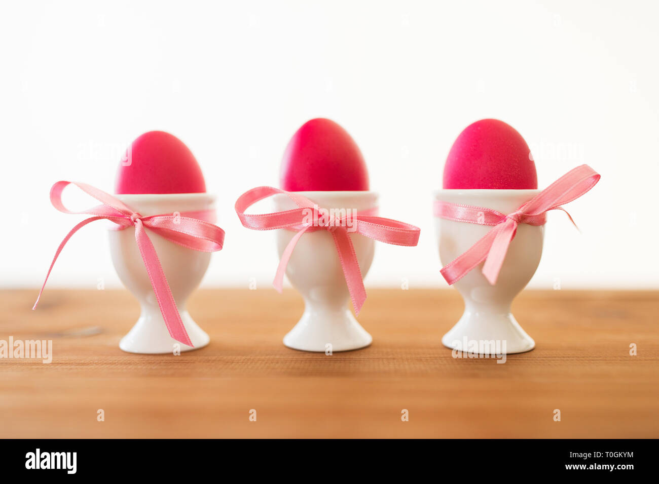three pink colored easter eggs in holders on table Stock Photo