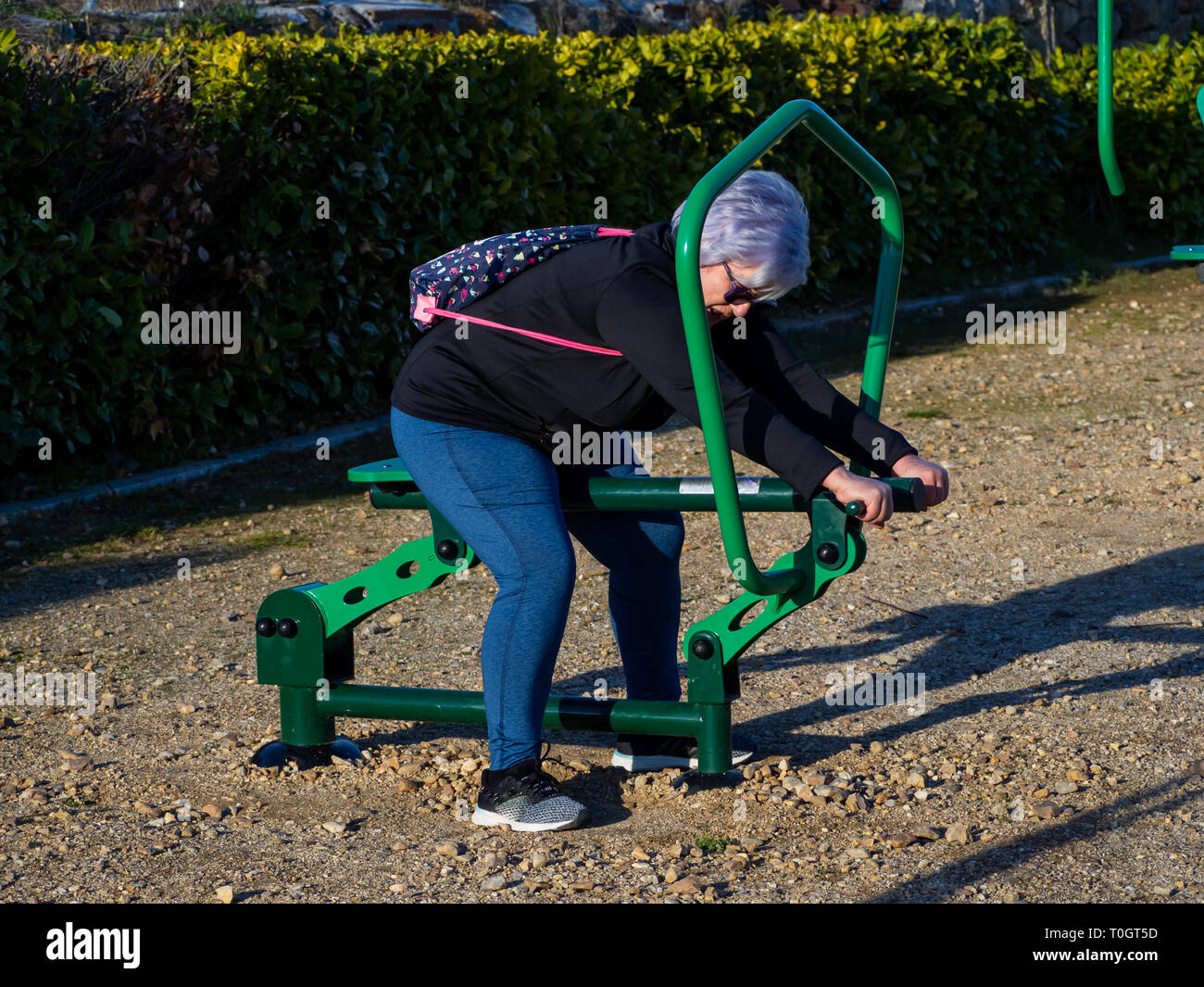 A senior woman with white hair practicing gymnastics in a bio-healthy park Stock Photo