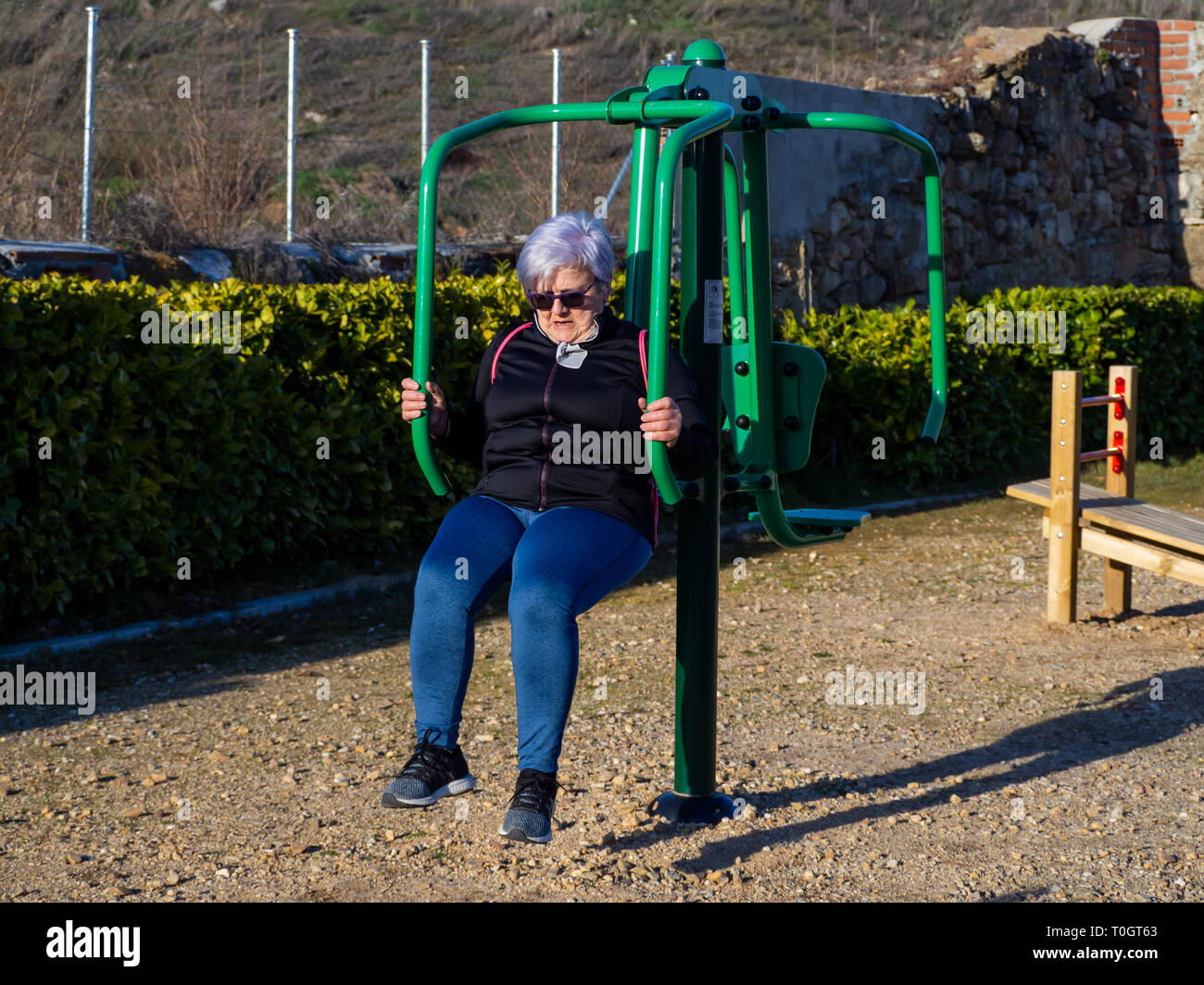 A senior woman with white hair practicing gymnastics in a bio-healthy park Stock Photo