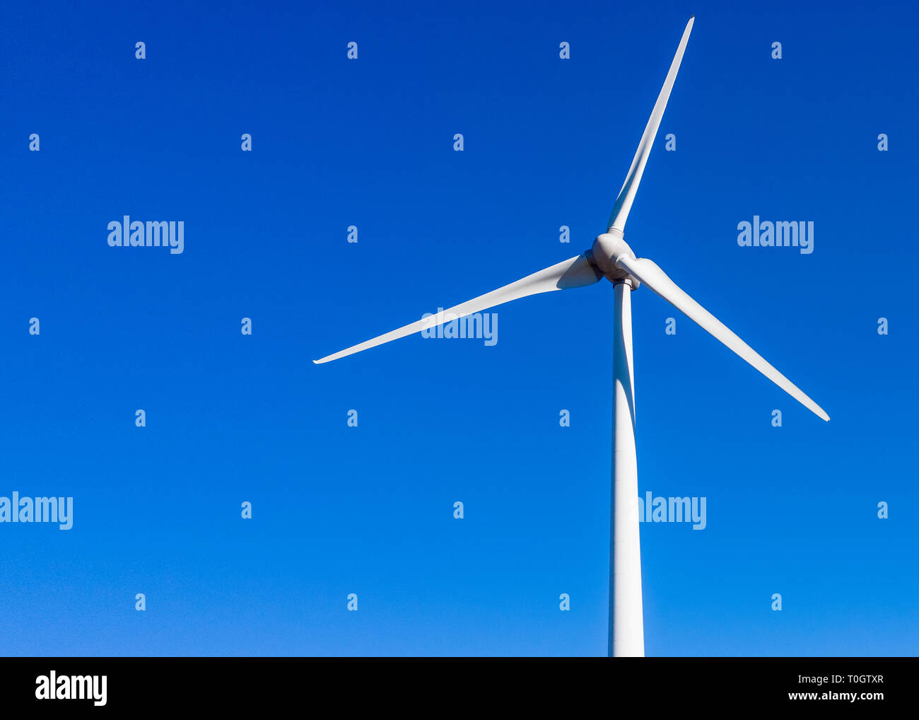 close up image of a single wind  turbine with a plain blue sky background  for copy space shot from above Stock Photo