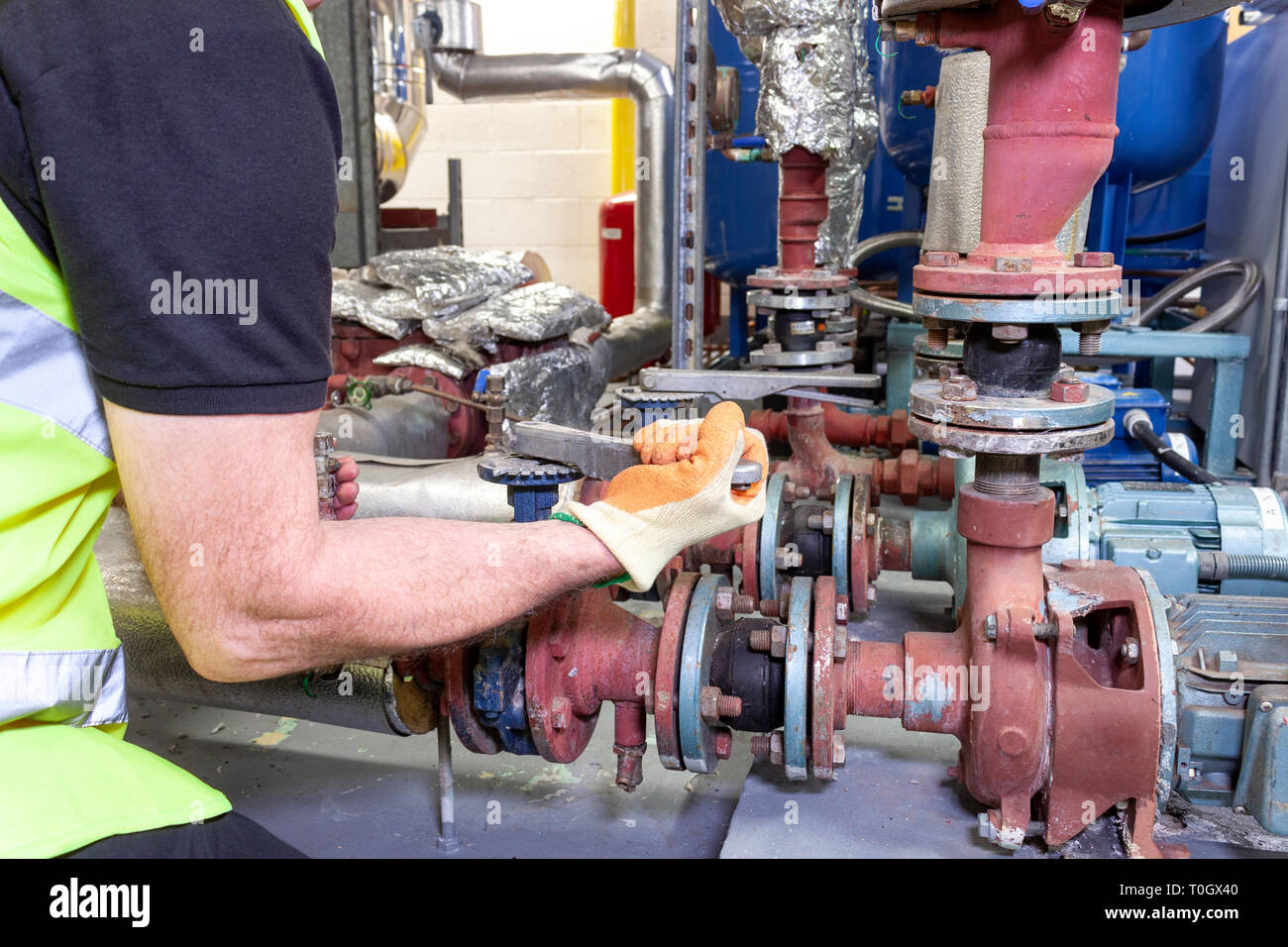 Mechanical engineer in a high visibility safety vest working on a pump set in a boiler room Stock Photo