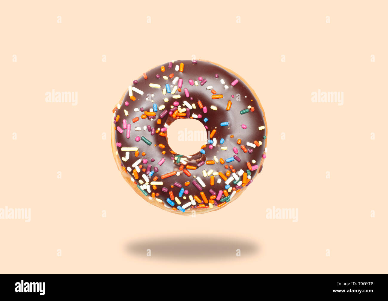 Chocolate donut with icing on pastel background. Stock Photo