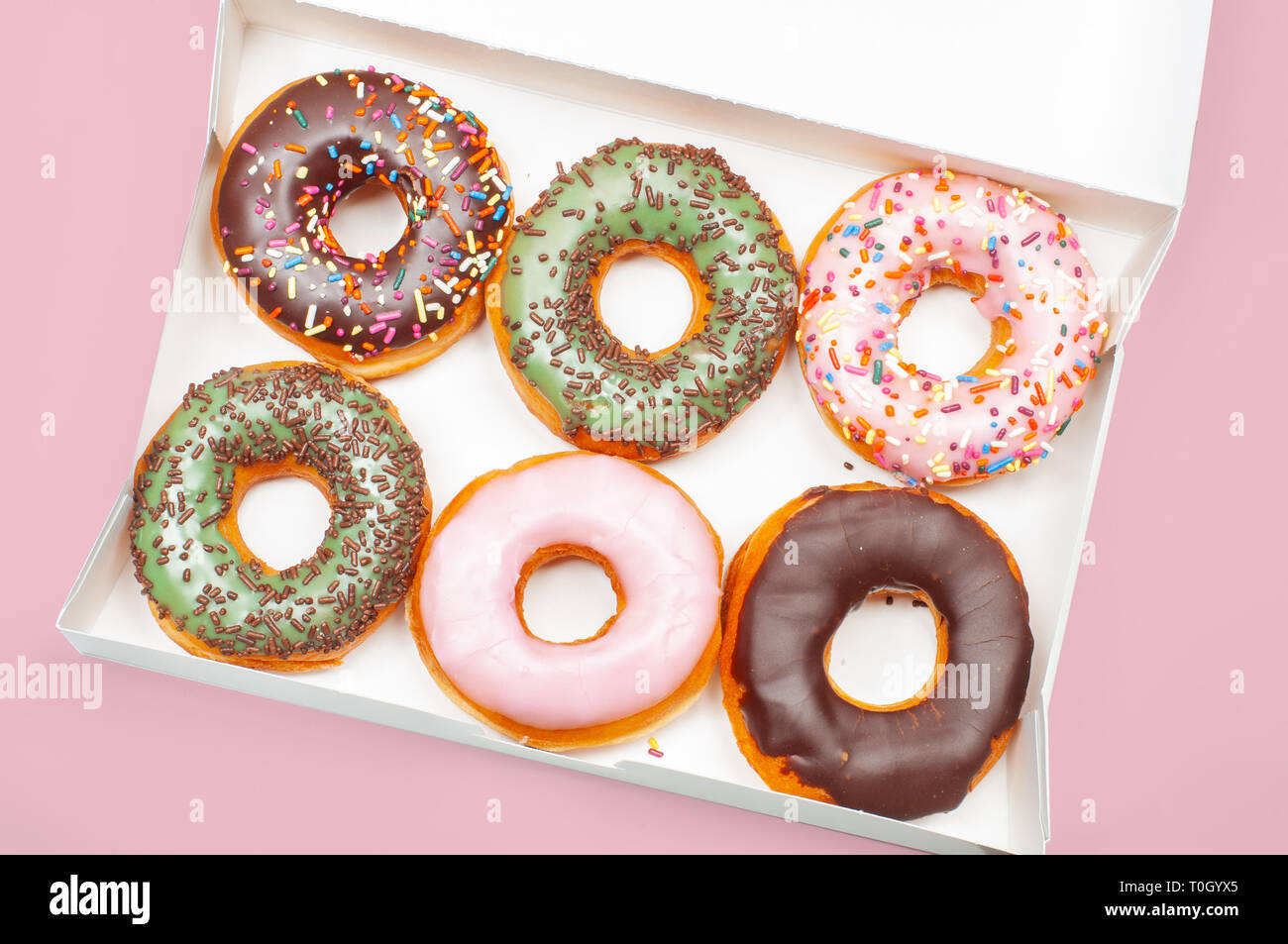 Colorful donuts in box on pastel pink background Stock Photo - Alamy