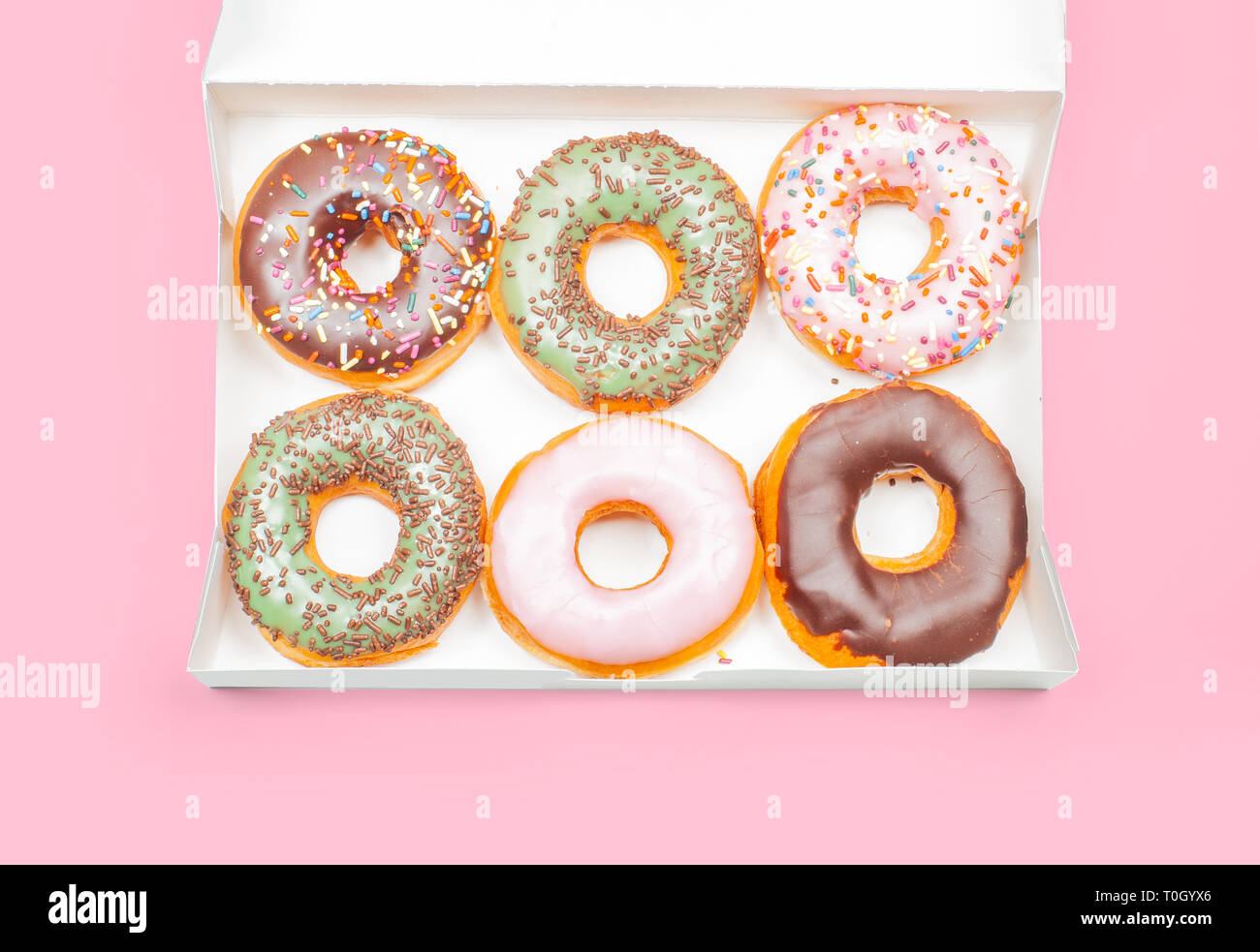 Colorful donuts in box on pastel pink background Stock Photo - Alamy