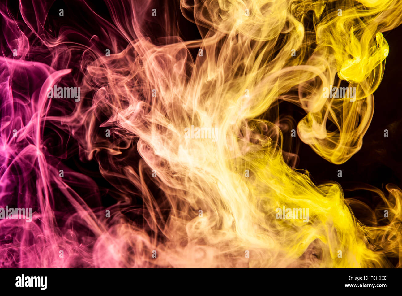 Abstract art colored pink and yellow smoke on black isolated background ...