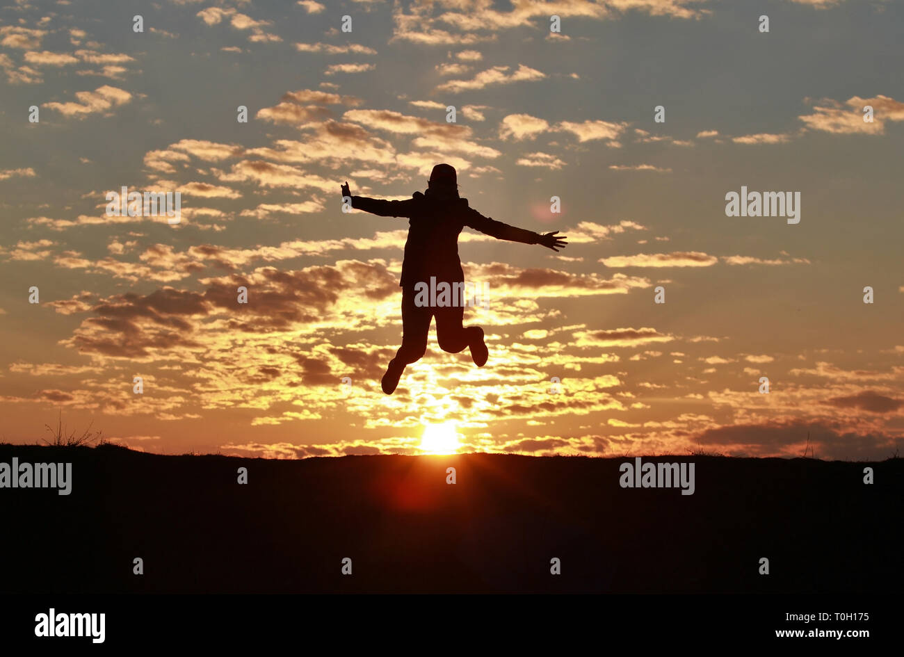 Silhouette of a happy girl jumping into the sky against the backdrop of ...