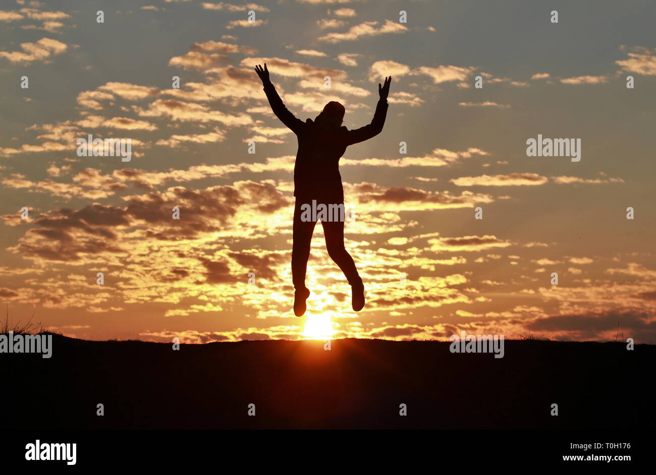 Silhouette of a happy girl jumping into the sky against the backdrop of ...