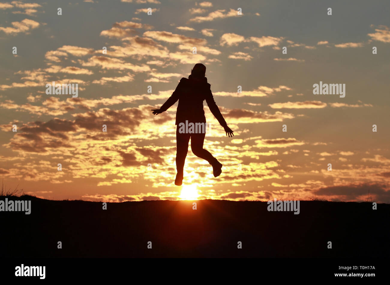 Silhouette of a happy girl jumping into the sky against the backdrop of ...