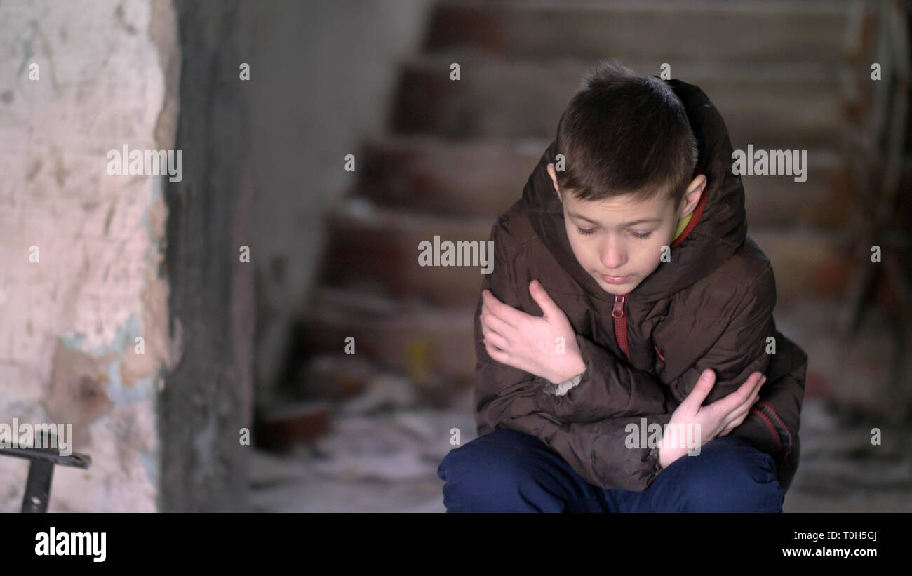 boy freezing in warm clothing in a dilapidated old house Stock Photo