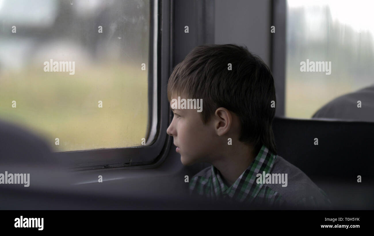 serious boy is traveling by train looks out the window Stock Photo