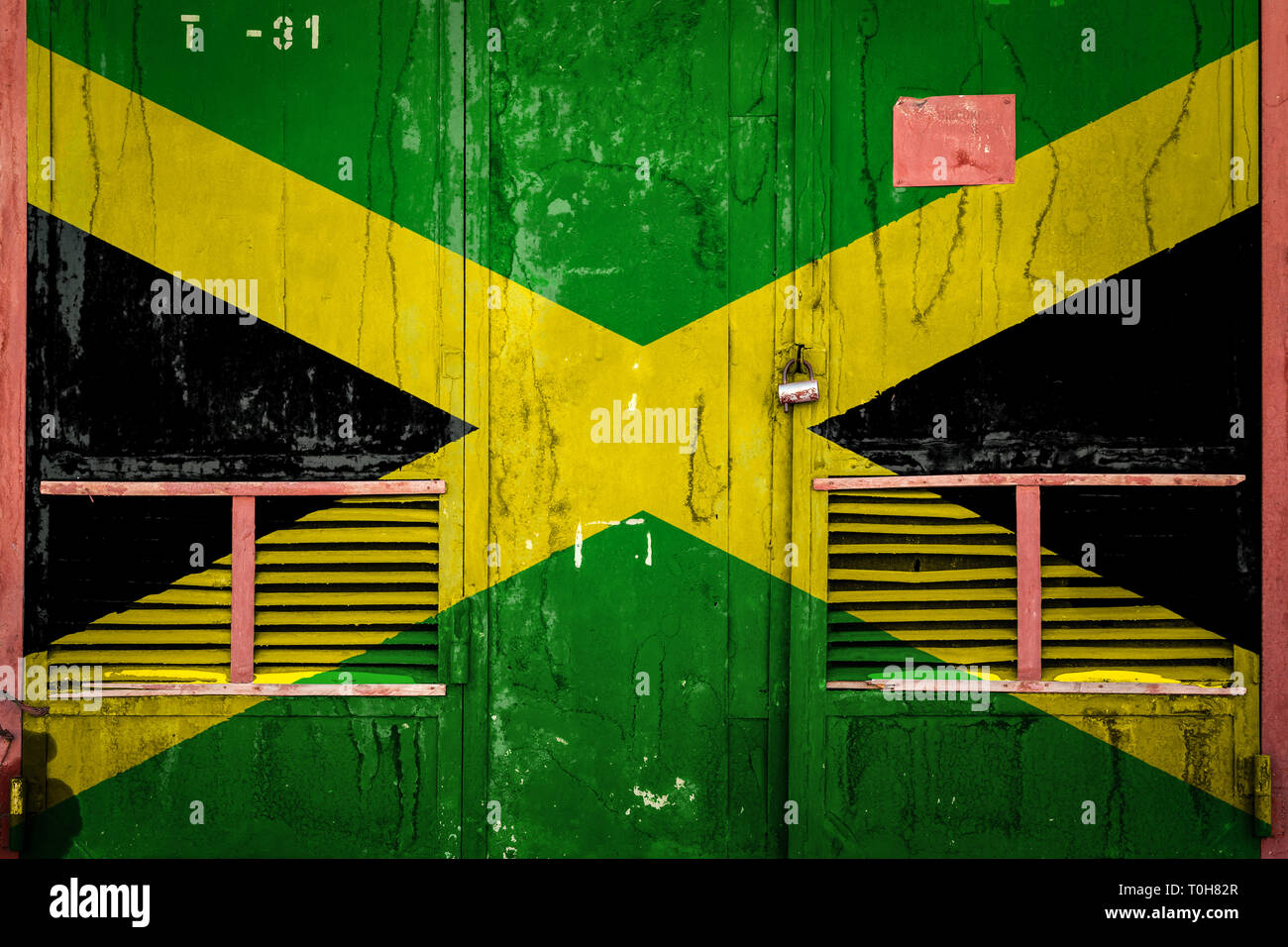 Closeup of old warehouse gate with national flag of Jamaica. Concept of Jamaica exportimport