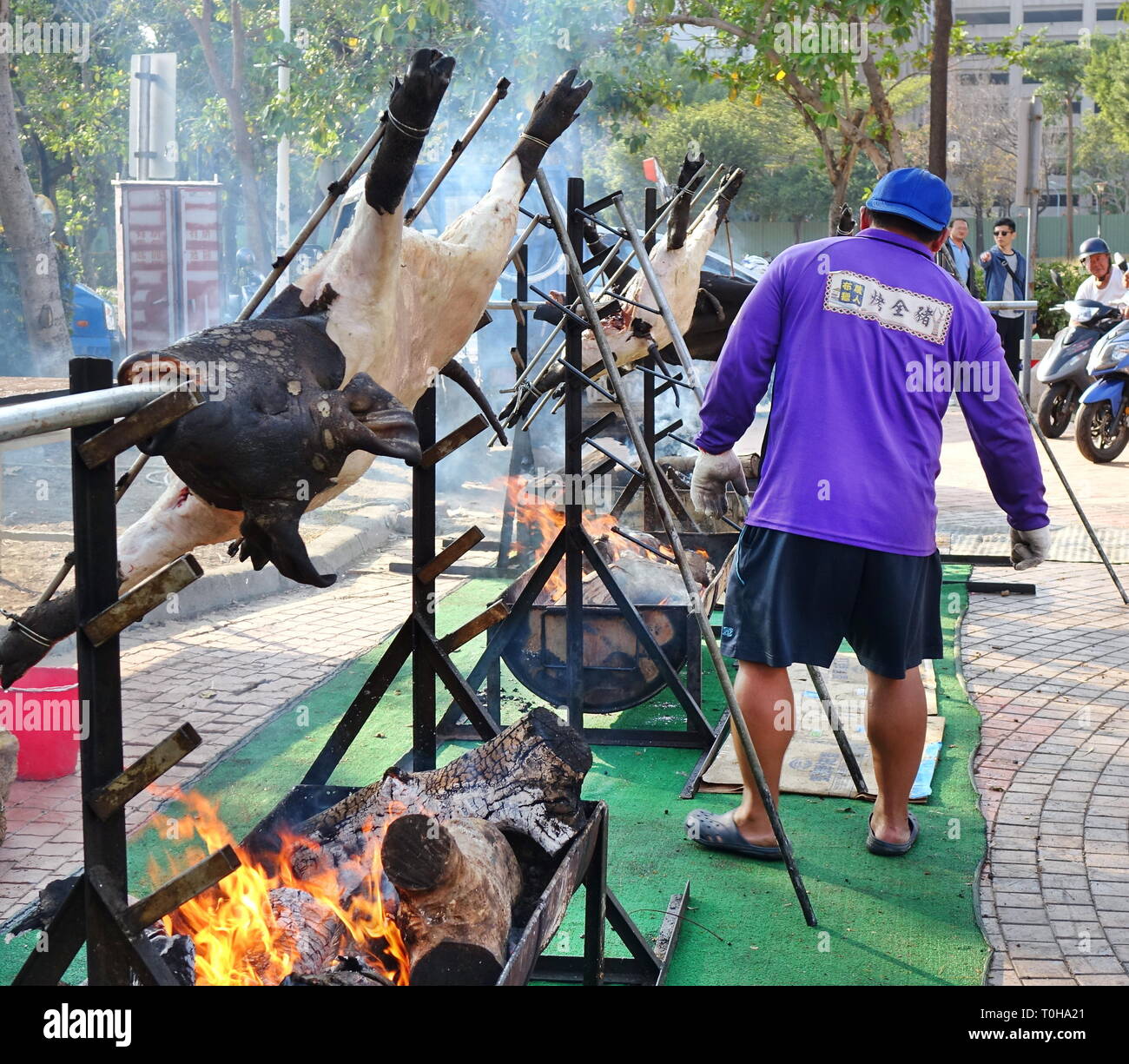 KAOHSIUNG, TAIWAN -- FEBRUARY 9, 2019: A member of Taiwan's indigenous people roasts whole pigs on the banks of the Love River during the Lantern Fest Stock Photo