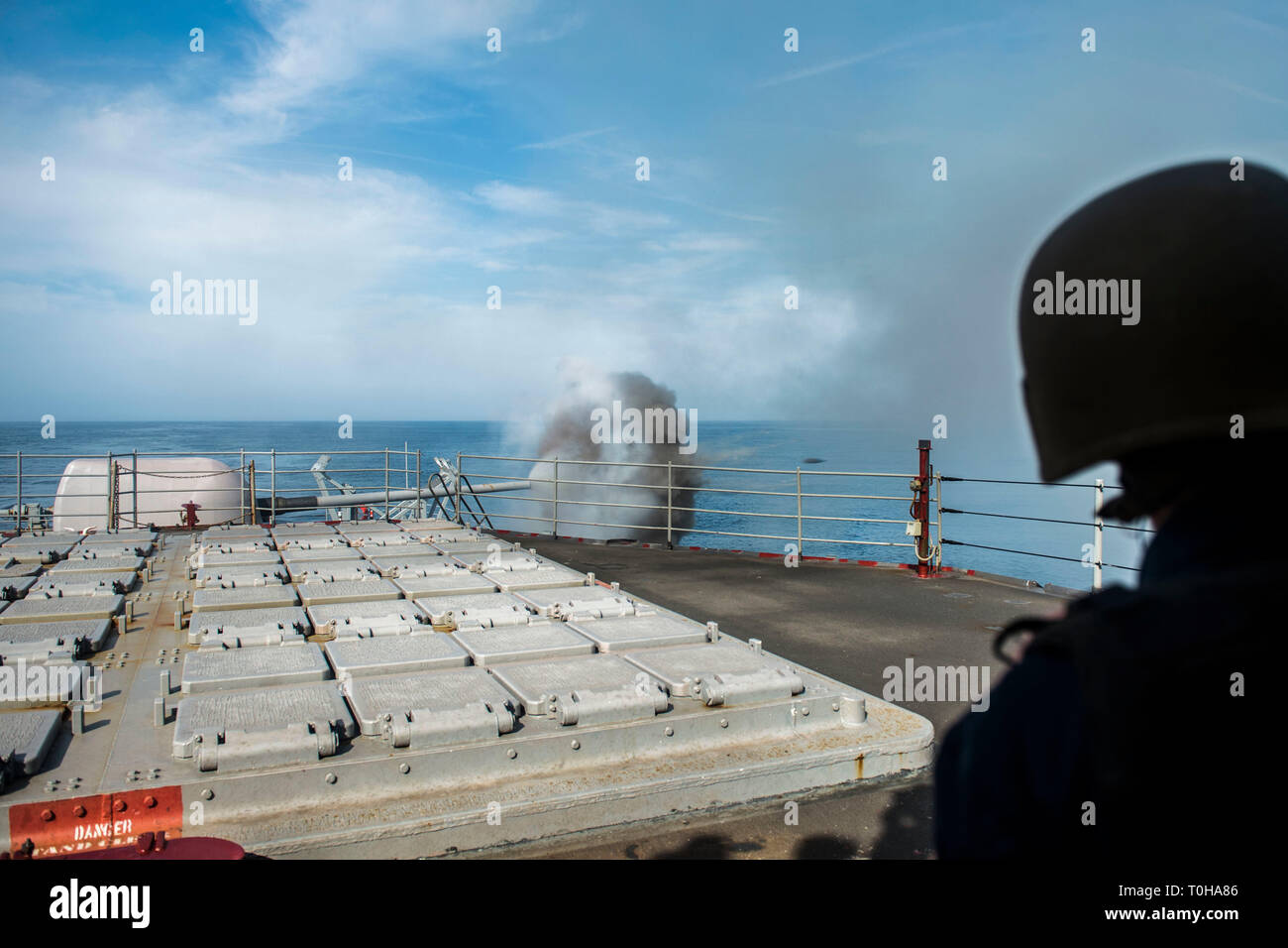 190311-N-AA191-0109 ATLANTIC OCEAN (March 11, 2019) A Sailor looks on as a  five-inch gun is fired during a live fire demonstration aboard the  guided-missile cruiser USS Hue City (CG 66). Hue City